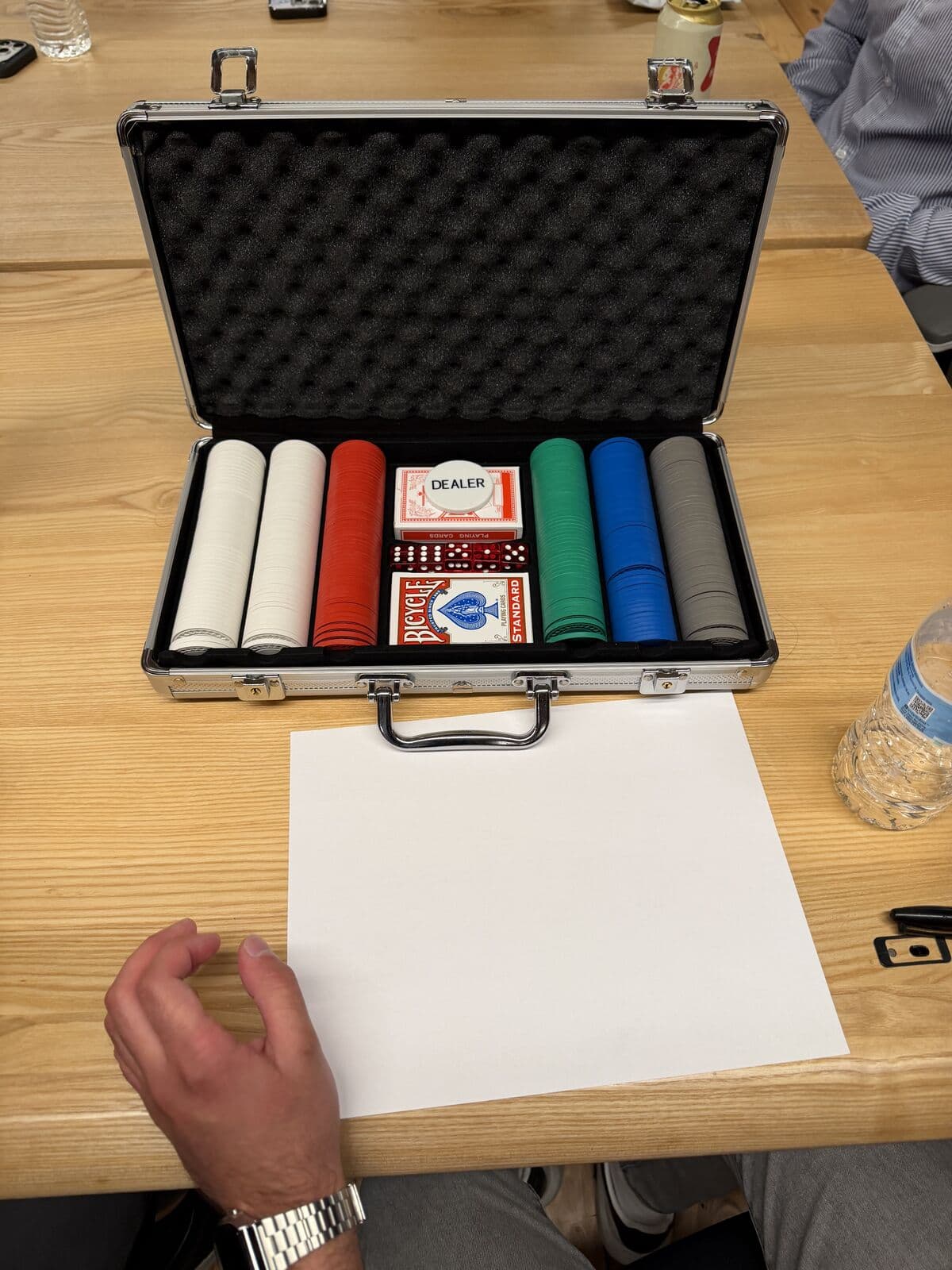 An open chip case with cards and the dealer button