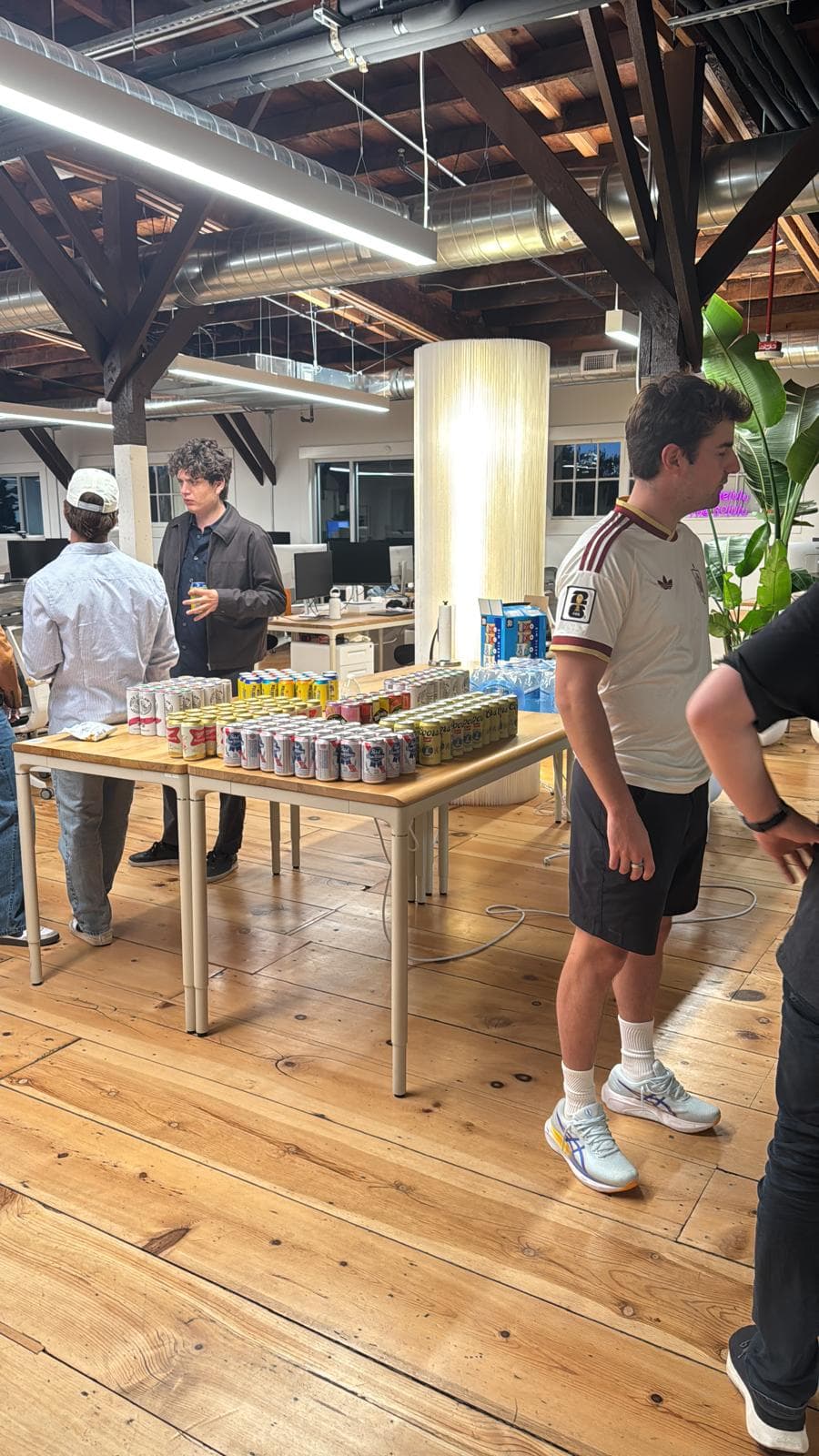 A table stacked with cans of drinks while guests mingle